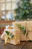 Gifts wrapped in brown paper with olive leaves and juniper sprigs