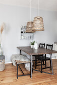Dining table with dark wooden top, black chairs, fur blanket on bench and pendant lamps