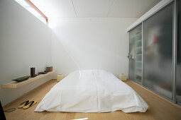 Doppelbett mit weißer Decke und Kleiderschrank mit satiniertem Glas im Schlafzimmer
