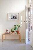 Bücher und Zimmerpflanzen vuf niedrigem Tisch aus hellem Holz vor Balkontür