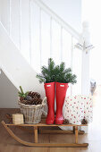 Wellie boots decorated with fir sprigs on a sledge against a flight of stairs