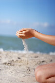 Hände spielen mit Sand am Strand