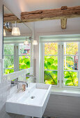 Waschbecken im Badezimmer mit Fenster und Holzbalken
