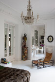 Vintage armchair and sculpture in a bedroom with chandelier, view into bathroom