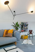 Grey sofa with scatter cushion below sculptural wall lamp in loft apartment