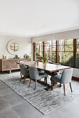 Wooden dining table and grey upholstered chairs next to window