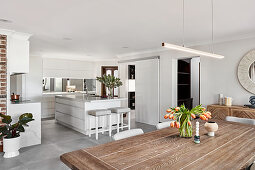 View across dining table into open-plan kitchen with island counter
