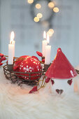 Metal basket as an Advent wreath with red and white Christmas tree baubles, rose hips and ceramic houses