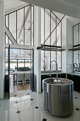 Round kitchen sink in elegant high-ceilinged kitchen with interior windows