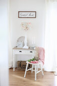 Pink tulips and wooden bunny on a white chair in front of a table with drawer