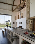 Kücheninsel mit Kalkstein-Arbeitsplatte und Esstisch in umgebauter Scheune