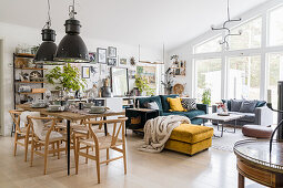 Classic chairs around dining table, above them industrial lamps, in the background seating area in open living room