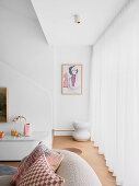 Hoher Wohnraum mit weißer Wand und bodenlangem, weißem Vorhang