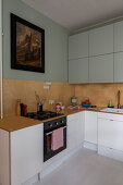 L-shaped kitchen counter below wooden splashback and vintage painting