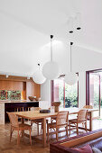 Dining area with wooden table and classic chairs, above lamps with paper shades