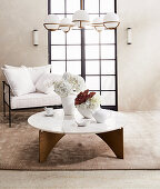 Vases on coffee table with marble top and designer chairs with white cushions