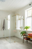 Ebenerdige Dusche mit Glaswänden und zwei goldenen Duschbrausen