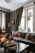 Weihnachtlich dekorierter Couchtisch und Sofa vor Fenster im Wohnzimmer mit Streifentapete