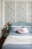 Bed and wood panelling with floral wallpaper in bedroom