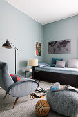 Bed, armchair and pouffe in teenager's bedroom with blue walls