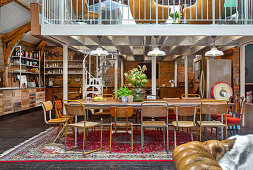 Open-plan, eclectic interior with long dining table below mezzanine