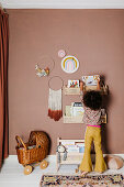 Dark-haired girl in front of bookshelves on brown wall in child's bedroom