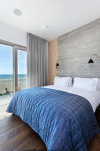 Blue quilt on bed in bedroom with sea view
