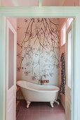 Freestanding vintage bathtub against photo wallpaper