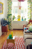 Living room with sofa, polka-dot rug, TV and colourful curtains