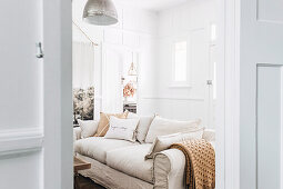 View into a white and beige living room with white paneled walls
