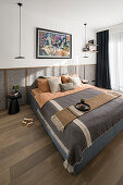 Doppelbett mit Kissen vor Wandverkleidung im Schlafzimmer