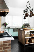 Kitchen with an island with a hanging cast iron pot rack and concrete countertops