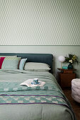Doppelbett in blau-grünen Tönen im Schlafzimmer mit farblich passender Tapete