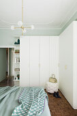 Weißer Eckschrank und Doppelbett im Schlafzimmer mit hellgrüner Wand