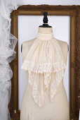 Lace jabot on an old dressmaker's dummy in front of a picture frame