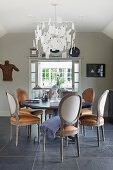 Wooden dining table and chairs with leather seats, above classic chandelier
