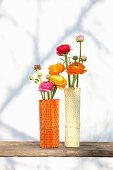 Ranunculus in glass vases, wrapped with folded and rolled paper