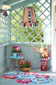 DIY lampshade made of pompoms and trims, flowers and colourful patchwork rug