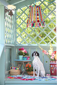 DIY lampshade made of pompoms and trims, flowers and dog sitting on colourful patchwork rug
