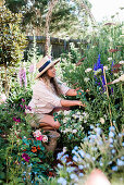 Frau bei der Gartenarbeit in blühendem Garten