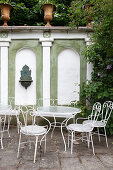 Klassische Gartenstühle mit Tischen vor Mauer, inspiriert von der italienischen Renaissance