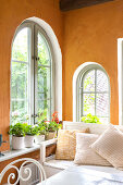 Orangerie mit gewölbten Fenstern und ockergelben Wänden
