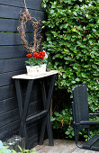 Narrow table with flower pot against a black-painted wooden wall