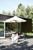 Table with chairs and parasol on wooden terrace