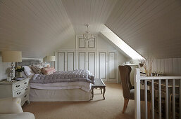 Großzügiges Schlafzimmer im Dachgeschoss mit Einbauschränken und heller Holzverkleidung
