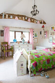 Holzbett mit bunter Decke und Puppenhäuschen im ländlichen Kinderzimmer