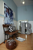 Vintage bench, above it modern art in a room with blue walls with white wainscoting