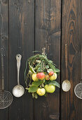 A bouquet of quinces and apples on a wooden door with kitchen utensils