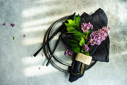 Spring place setting with lilac flowers on concrete background