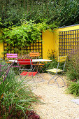 Seat in front of yellow painted wall with trellis (Appeltern, Netherlands)